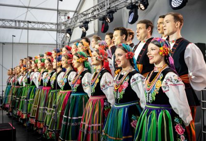 Cały chór w kostiumach łowickich z perspektywy boku sceny