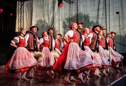 Grupa Artystów w dwóch rzędach na scenie w kostiumach jurgowskich wykonująca choreografię taneczną