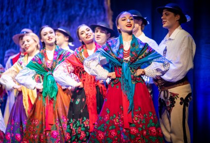 Artyści w kostiumach podhalańskich w trakcie wykonywania choreografii tanecznej wraz ze śpiewem