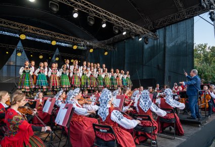 Widok na orkiestrę z Dyrektorem Jackiem Bonieckim i chór na scenie w kostiumach łowickich
