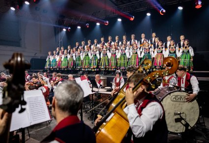 Na pierwszym planie Artyści orkiestry w kostiumach wilanowskich, w tle Artyści Chóru w kostiumach łowickich