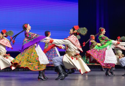 Pary Artystów w kostiumach krakowskich podczas wykonywania choreografii tanecznej na scenie