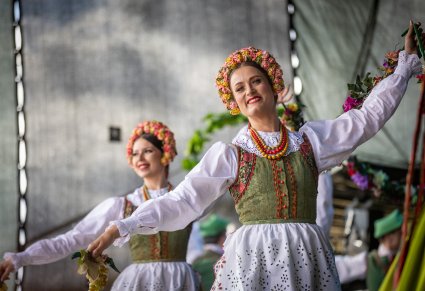 Zbliżenie na dwie Artystki w kostiumach lubuskich na scenie wykonujące choreografię taneczną