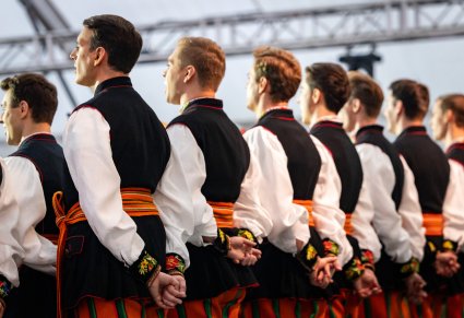 Widok od tyłu na chórzystów w kostiumach łowickich