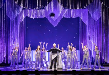 Na scenie na środku postać Księżyca a wkoło niego postać gwiazd w srebrnych, świecących kostiumach