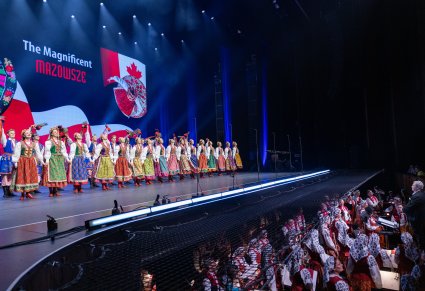 Na scenie Artyści w kostiumach krakowskich podczas finałowego ustawienia choreografii Krakowiaka, widoczna część orkiestronu z Muzykami i Dyrygentem