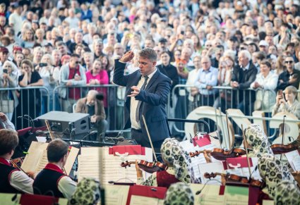 Widok na część orkiestry w kostiumach wilanowskich, dyrygenta, a także publiczność w tle