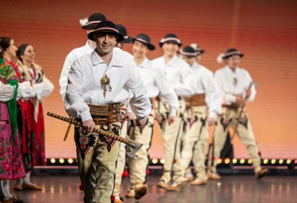 Na scenie grupa Artystów w kostiumach podhalańskich podczas wykonywania choreografii tanecznej