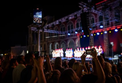 Zbliżenie na publiczność, która robi zdjęcia sceny telefonami komórkowymi