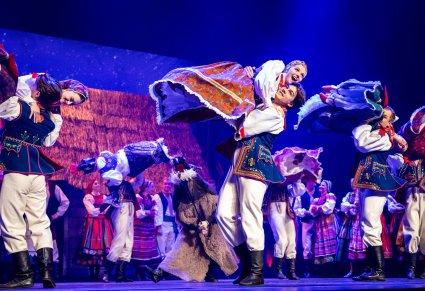 Na scenie Artyści w kostiumach ludowych wraz z postacią Turonia w trakcie wykonywania choreografii tanecznej