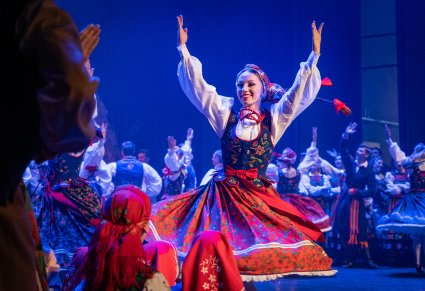 Na pierwszym planie Artystka w kostiumie limanowskim w trakcie wykonywania choreografii tanecznej