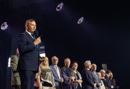 Na pierwszym planie przemawiający do mikrofonu wicemarszałek województwa mazowieckiego wraz z lokalnymi działaczami na scenie