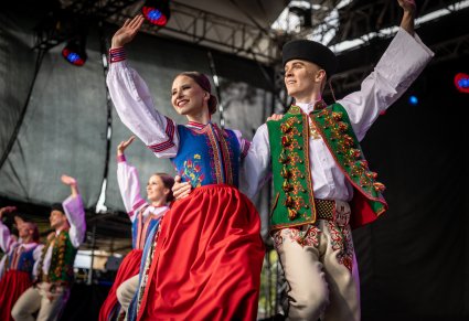 Pary Artystów w kostiumach spiskich na scenie, machający w stronę publiczności