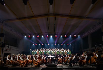Szeroki plan na scenę na której znajdują się Artyści Chóru w kostiumach łowickich, Orkiestra w kostiumach wilanowskich