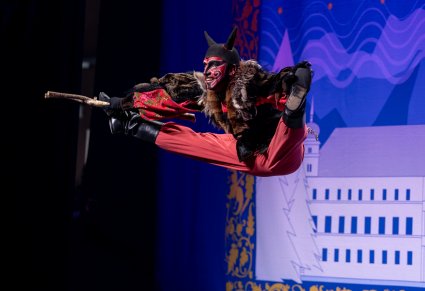 Postać Diabła Ludowego wykonująca w górze figury akrobatyczne