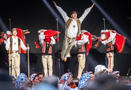 Tancerze tańczący choreografię w kostiumach jurgowskich widoczna orkiestra