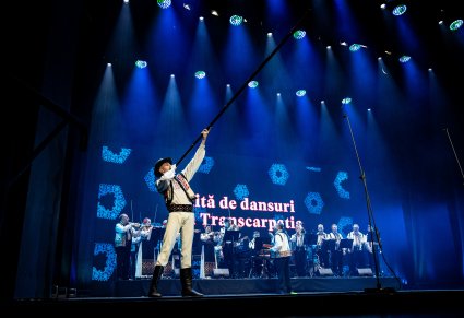 Artysta baletu Mołdawii w tradycyjnym kostiumie gra na długim instrumencie dętym