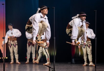 Zbliżenie na Artystów w kostiumach podhalańskich w trakcie przeskakiwania przez ciupagi