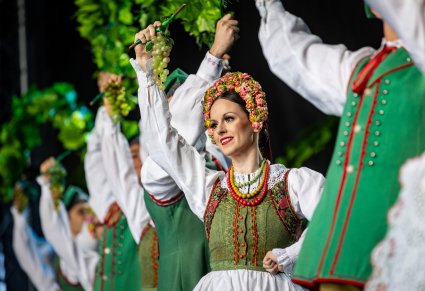 Artyści na scenie w kostiumach lubuskich trzymający w górze element dekoracji