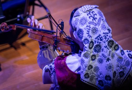 Zbliżenie na Muzyczkę w kostiumie wilanowskich, grającą na instrumencie smyczkowym