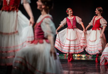 Dwie Artystki wykonujące choreografię taneczną na scenie w kostiumach stylizowanych na kostium krakowski