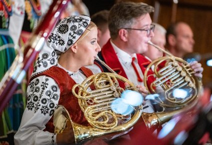 Artyści Orkiestry w kostiumach wilanowskich dmuchający w waltornię