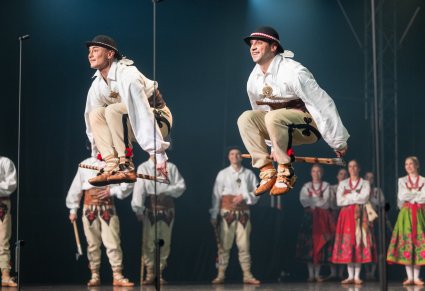 Na pierwszym planie dwóch Artystów w kostiumach podhalańskich podczas wykonywania spektakularnych figur tanecznych