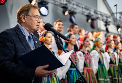 Konferansjer podczas koncertu, w tle widoczna część chóry w kostiumach łowickich
