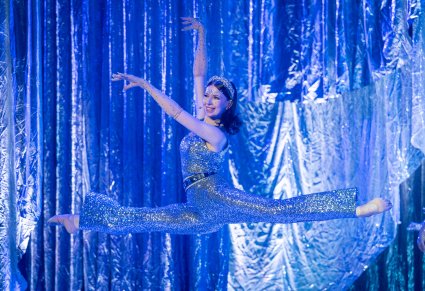 Artystka występująca w roli jednej z gwiazd w trakcie wykonywania figury akrobatycznej w górze