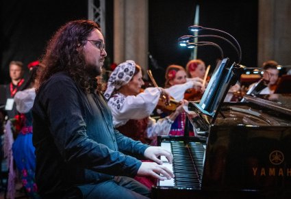 Na pierwszym planie akompaniator a w tle orkiestra