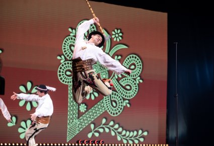 Zbliżenie na Artystę w kostiumie podhalańskich podczas wykonywania figur tanecznych