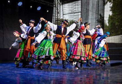 Grupa Artystów w kostiumach łowickich na scenie wykonująca choreografię taneczną