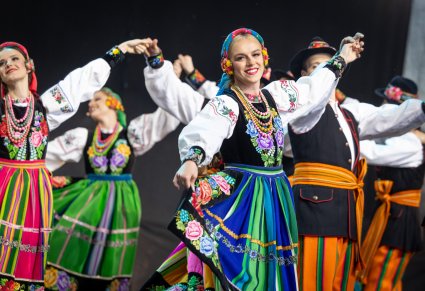 Zbliżenie na pary Artystów w kostiumach łowickich podczas wykonywania choreografii tanecznej