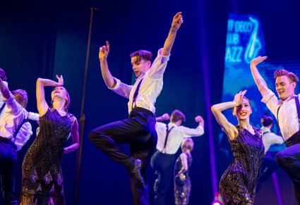 Zbliżenie na Artystów w kostiumach stylizowanych latami 20stymi w trakcie wykonywania choreografii tanecznej
