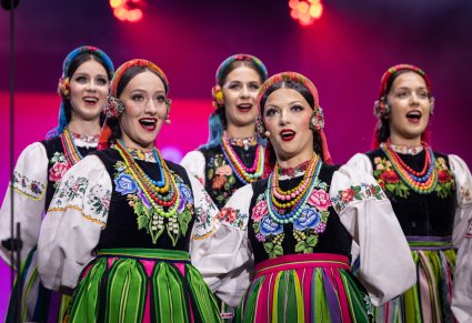 Zbliżenie na dwie Solistki w kostiumach łowickich, za nimi część Artystek Chróru