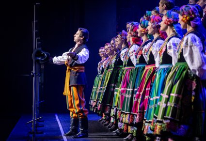 Solista chóru podczas występu na koncercie, za nim widoczny chór