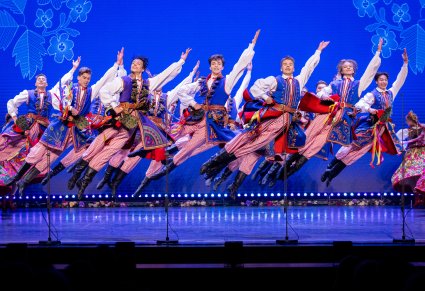 Grupa Artystów w kostiumach krakowskich w trakcie wykonywania choreografii tanecznej