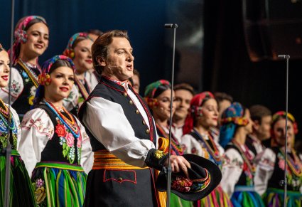 Zbliżenie na Solistę, za nim Artyści chóru w kostiumach łowickich