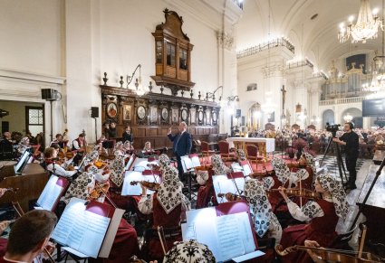 Na pierwszym planie Artyści Orkiestry w kostiumach wilanowskich, skierowany w ich kierunku Dyrygent, Dyrektor zespołu "Mazowsze", a w tle widoczna część Publiczności