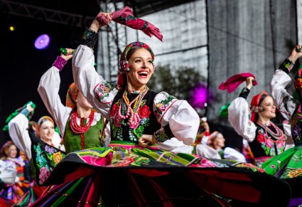 Uśmiechnięte Artystki w kostiumach łowickich na scenie w trakcie choreografii