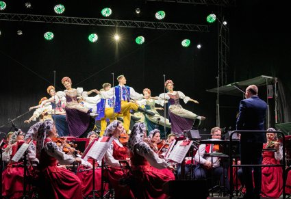 Widok na część baletu w kostiumach opolskich, podczas tańca na scenie, poniżej częśc orkiestry w kostiumach wilanowskich  wraz z dyrygentem