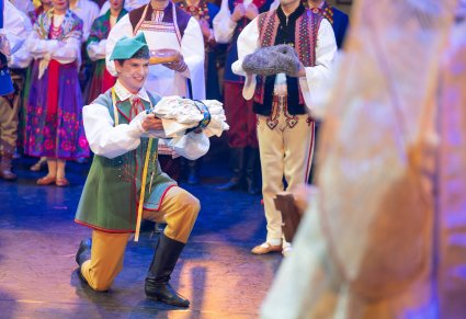 Zbliżenie na klęczącego Krawca, który trzyma w dłoniach prezent dla Jezuska