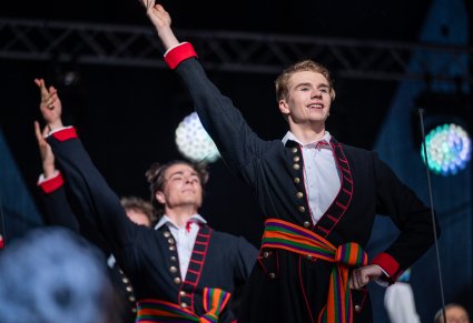 Przybliżenie na dwóch artystów na scenie w kostiumie łowickim