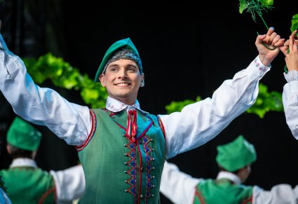 Uśmiechnięty Artysta w kostiumie lubuskim na scenie w trakcie wykonywania choreografii tanecznej