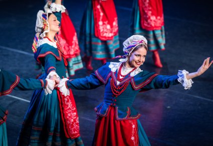 Zbliżenie na Artystki w kostiumach kujawskich w trakcie wykonywania choreografii tanecznej na scenie
