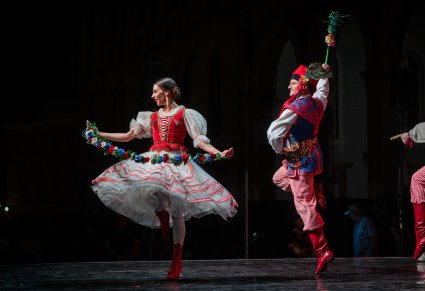 Dwójka Artystów wykonująca choreografię taneczną na scenie w kostiumach stylizowanych na kostium krakowski