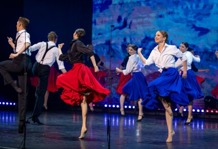 Na scenie grupa Artystów w kostiumach współczesnych podczas wykonywania choreografii tanecznej