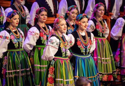 Na pierwszym planie Solistki a w tle część Artystów Chóru w kostiumach łowickich