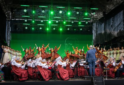 Na scenie Artyści chóru w kostiumach stylowych z końca XIX wieku, Artyści Baletu w kontuszach w trakcie wykonywania choreografii tanecznej oraz Artyści Orkiestry w kostiumach wilanowskich wraz z Dyrygentem, trzymającym w górze batutę