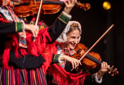 Zbliżenie na uśmiechniętą, grającą skrzypaczkę w kostiumie lubuskim
